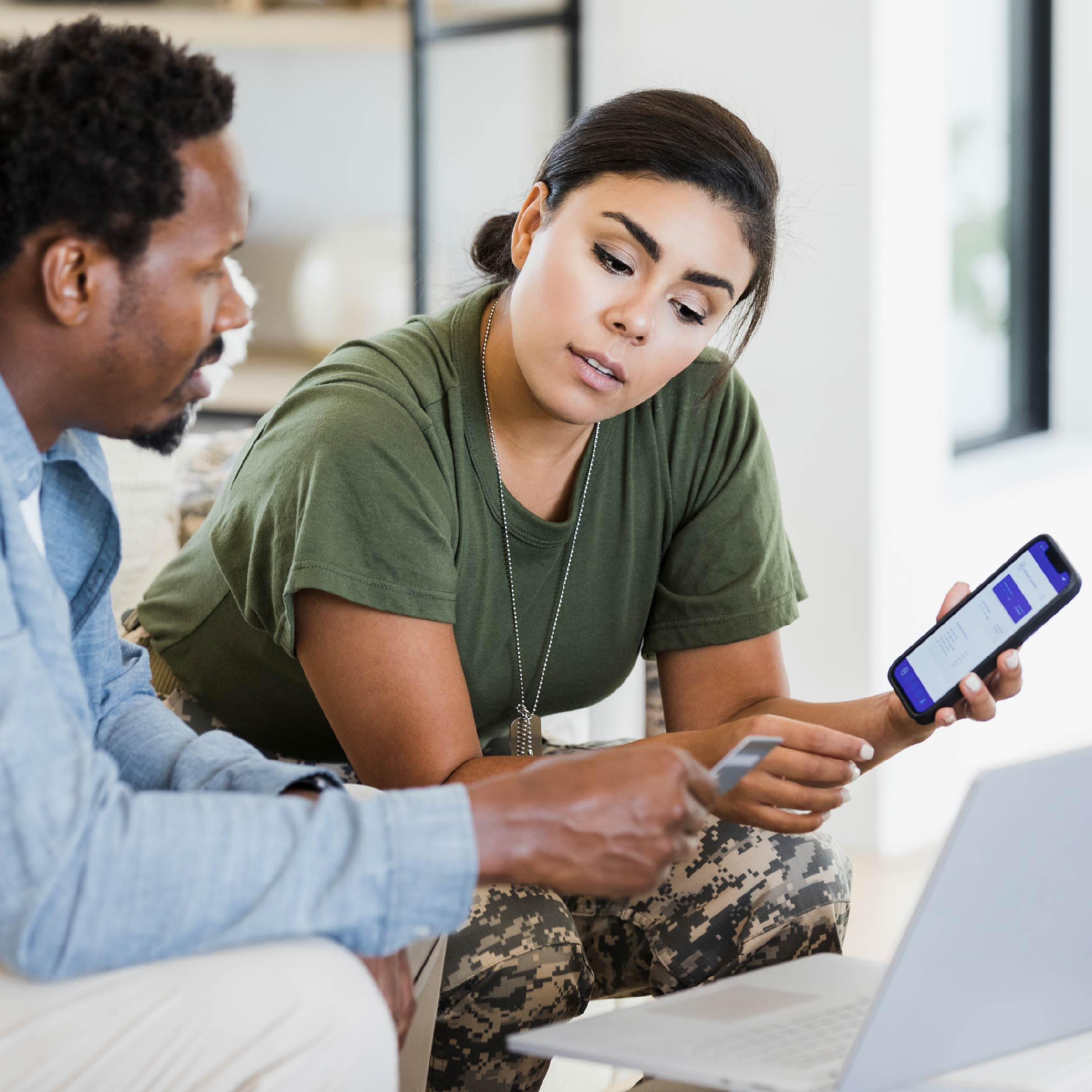 female soldier holding mobile phone taking a payment from a person holding a credit card