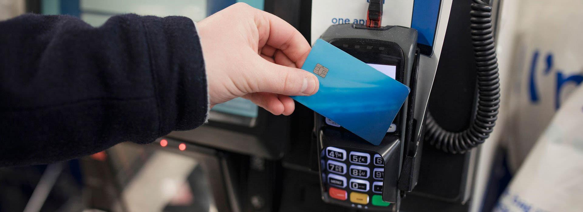 hand with credit card doing tap to pay at gas station