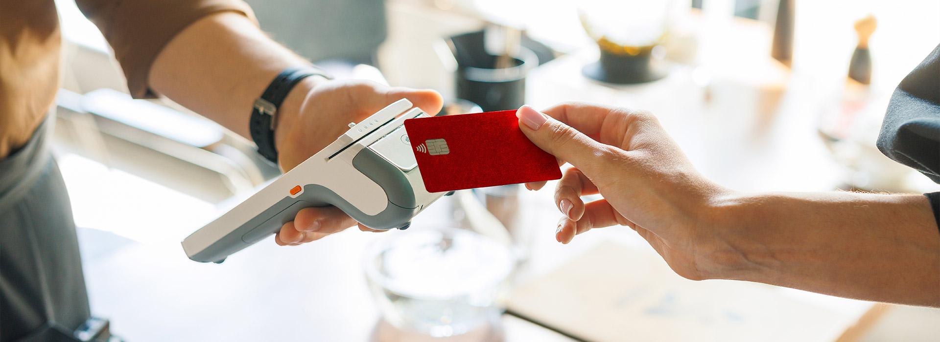 Red credit card being presented for a retail financial transaction